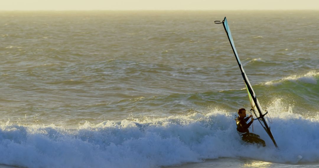 Windsurfer Navigating Waves in Golden Hour Light - Free Images, Stock Photos and Pictures on Pikwizard.com