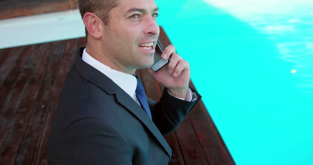 Businessman Taking a Call by Poolside Deck - Free Images, Stock Photos and Pictures on Pikwizard.com