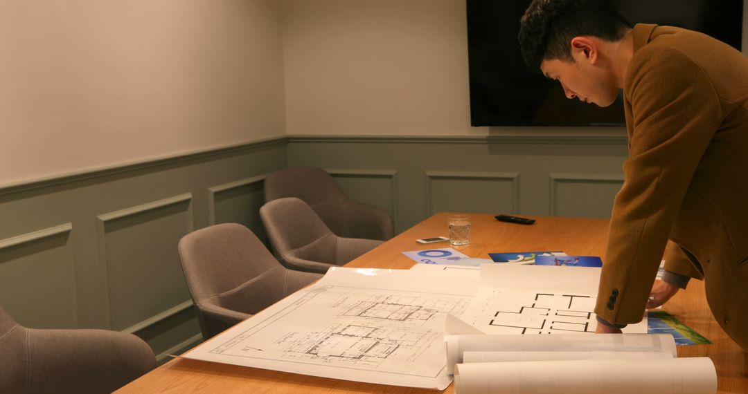 Architect Examining Blueprints in Office Meeting Room - Free Images, Stock Photos and Pictures on Pikwizard.com