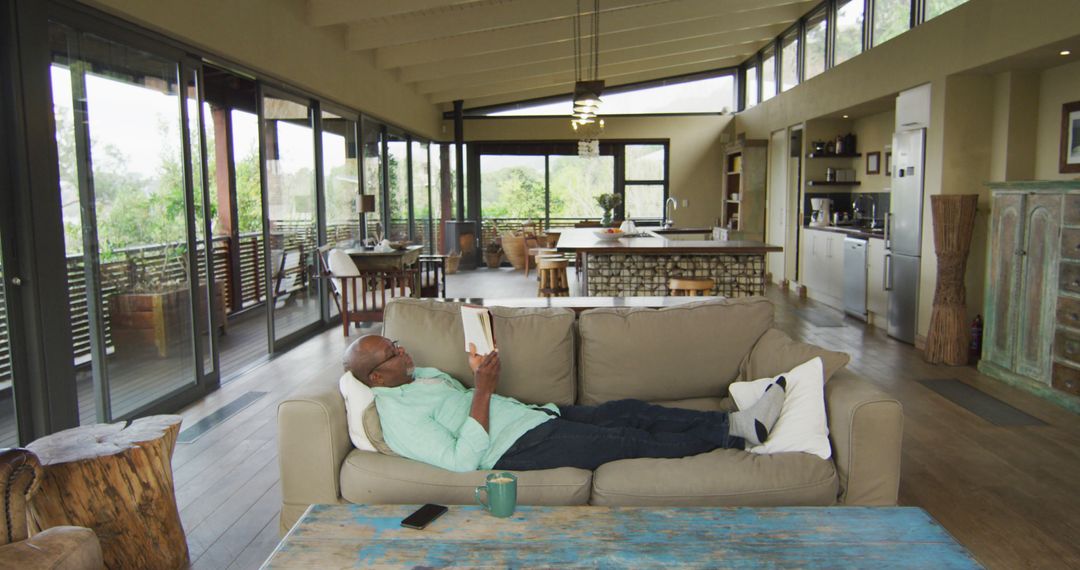 Man Relaxing on Couch Reading Tablet in Modern Living Room - Free Images, Stock Photos and Pictures on Pikwizard.com