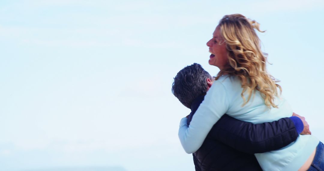 A joyful hug between a middle-aged woman and a man signifies a warm reunion under a clear sky. - Free Images, Stock Photos and Pictures on Pikwizard.com