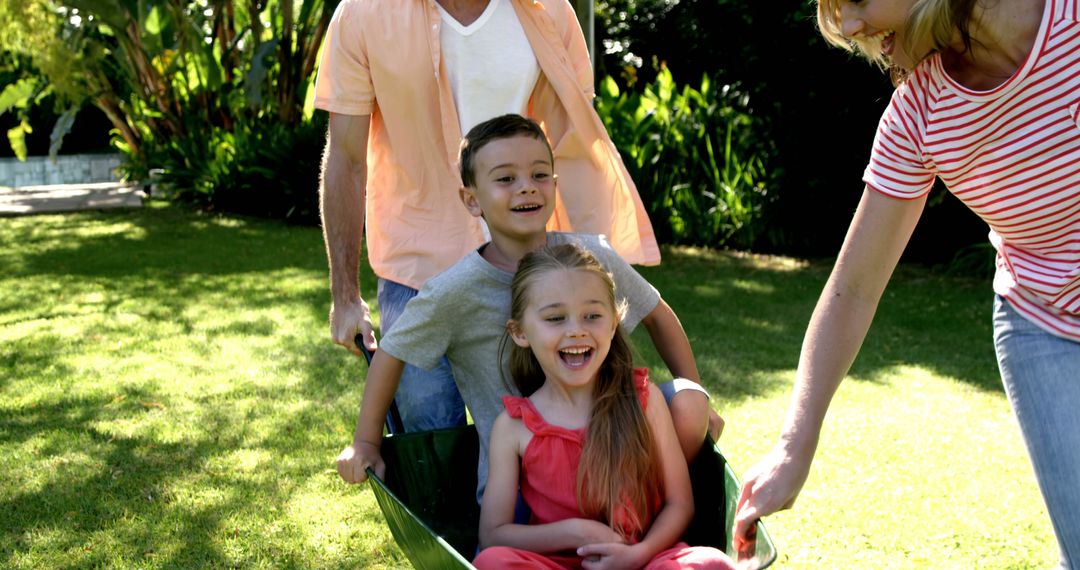 Happy Family Playing with Wheelbarrow in Sunny Backyard - Free Images, Stock Photos and Pictures on Pikwizard.com