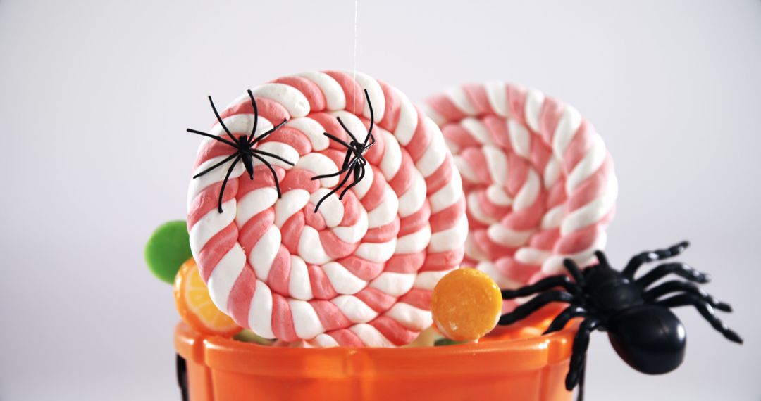 Halloween candy spirals with plastic spiders evoke a playful yet eerie festive vibe. - Free Images, Stock Photos and Pictures on Pikwizard.com