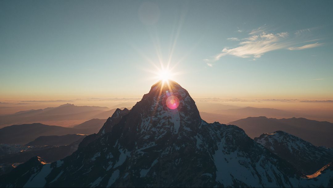 Sunrise Illuminating Snow-Dusted Mountain Peak with Flare