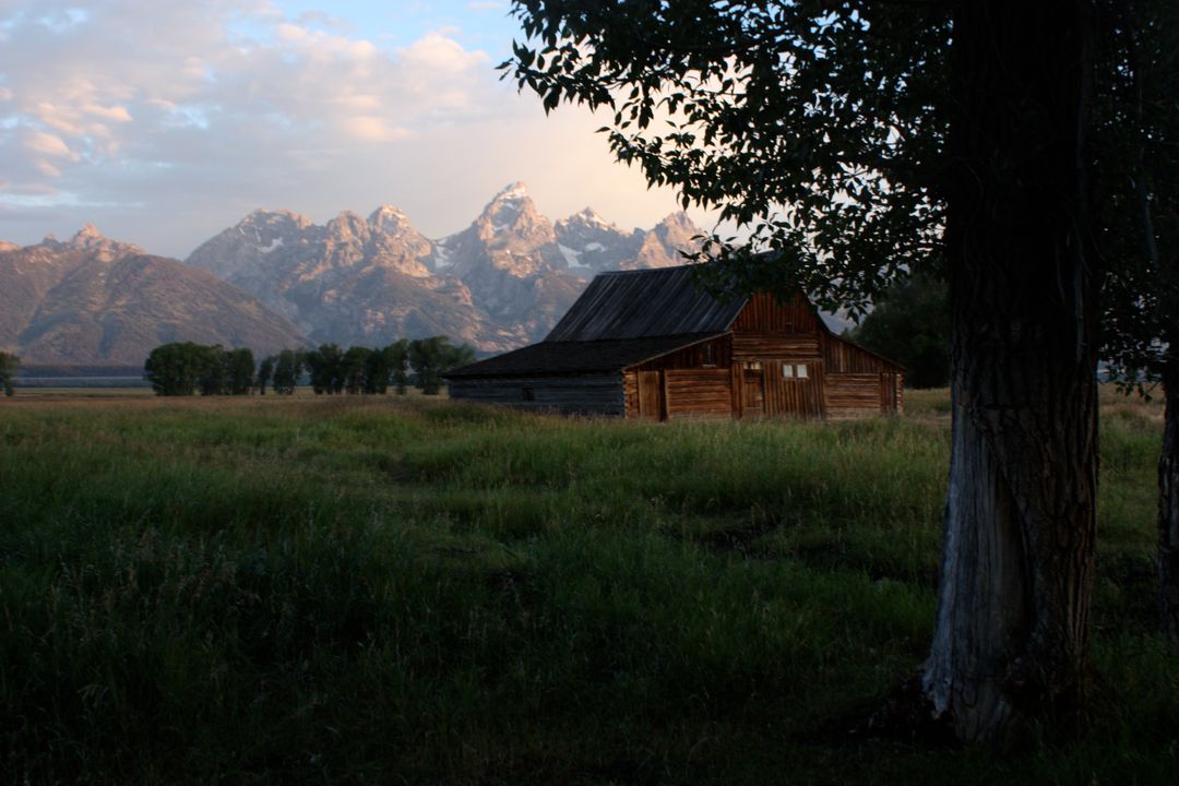 Rustic Barn Amidst Lush Field with Majestic Mountain Background - Free Images, Stock Photos and Pictures on Pikwizard.com
