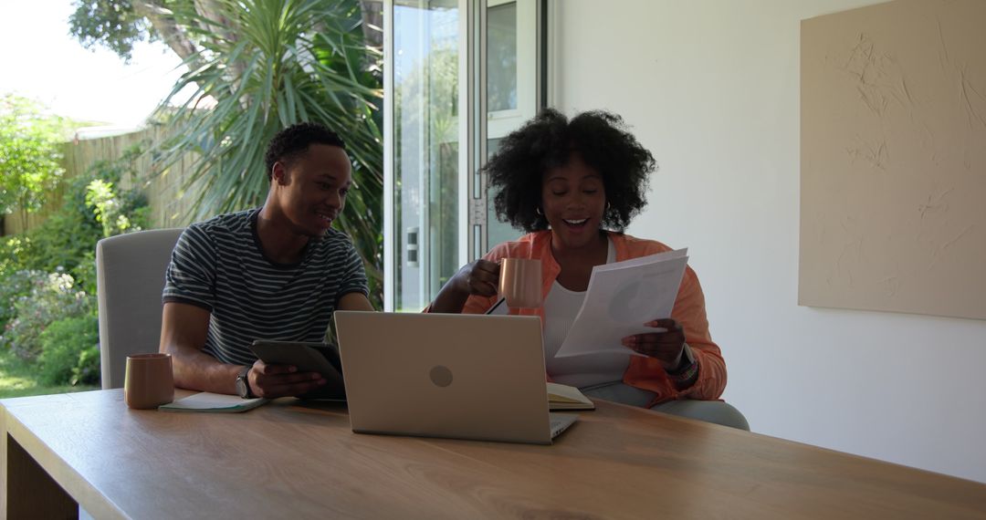 Couple Collaborating Over Laptop and Documents at Home