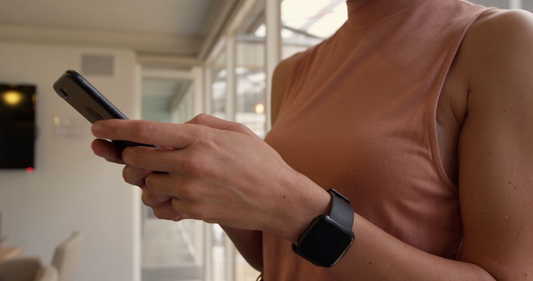 Woman Wearing Fitness Watch Using Smartphone Indoors - Free Images, Stock Photos and Pictures on Pikwizard.com