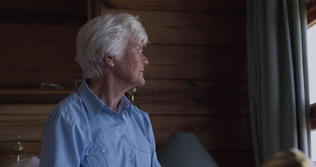 Senior Woman in Thoughtful Reflection by Window Pane