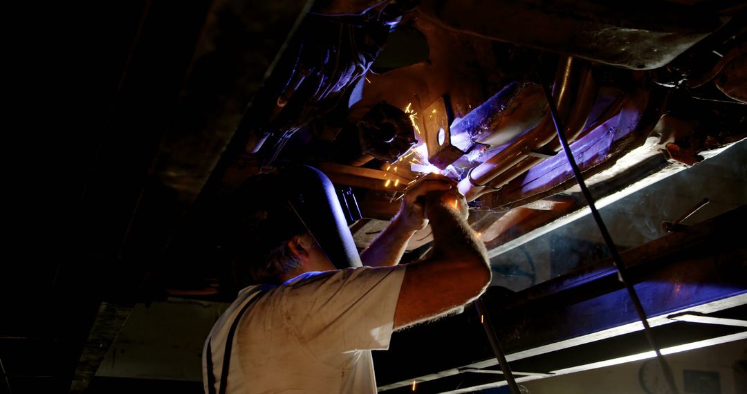 Mechanic Welding Car Undercarriage in Dark Workshop - Free Images, Stock Photos and Pictures on Pikwizard.com