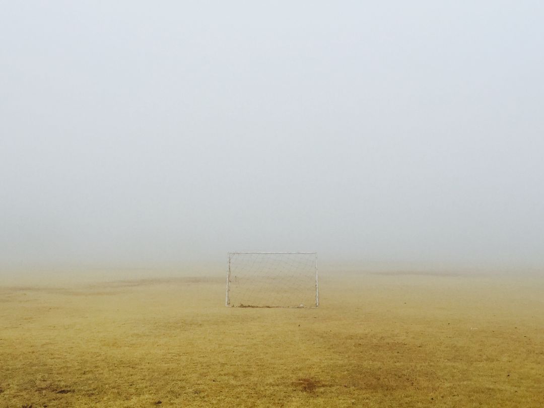 Solitary soccer goal standing on foggy golden field evoking solitude and quiet minimalist sports sce
