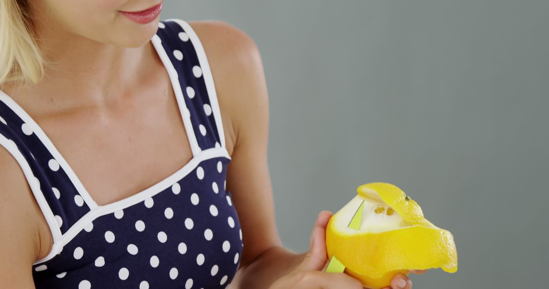 Woman in Polka Dot Top Peeling Lemon Against Grey Background - Free Images, Stock Photos and Pictures on Pikwizard.com