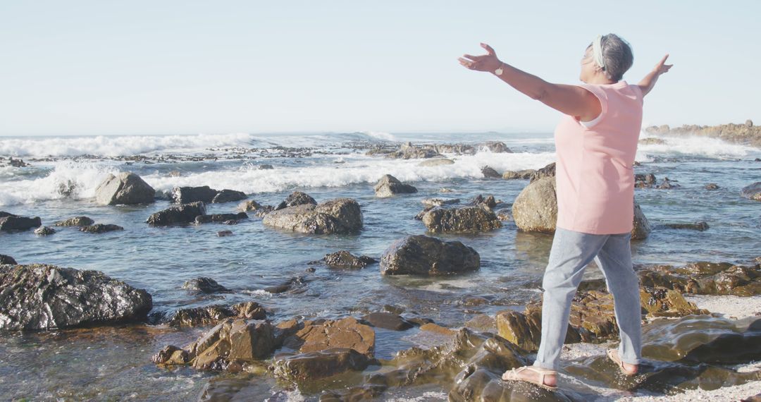 Senior Woman Embracing Nature at Rocky Shore in Casual Clothes - Free Images, Stock Photos and Pictures on Pikwizard.com