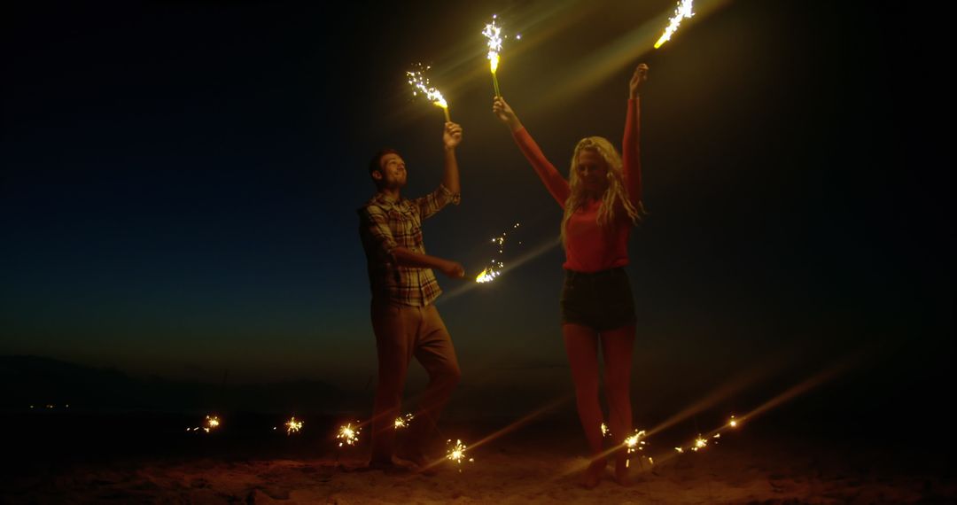 Young Couple Dancing with Sparklers on Beach at Dusk