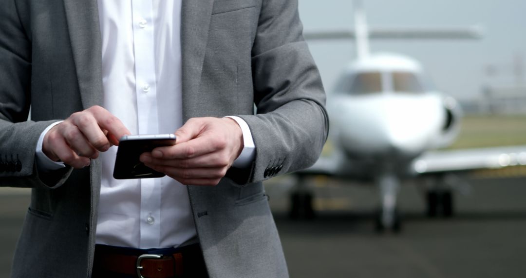 Businessman Checks Phone Next to Private Jet