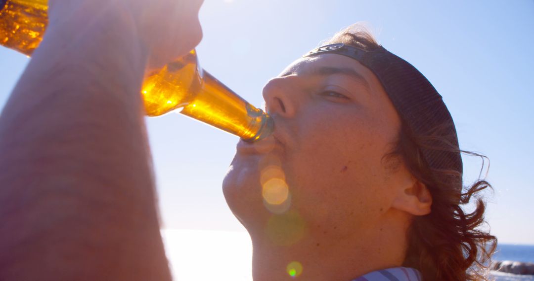 Young Man Drinking Beer on Sunny Day at Beach - Free Images, Stock Photos and Pictures on Pikwizard.com