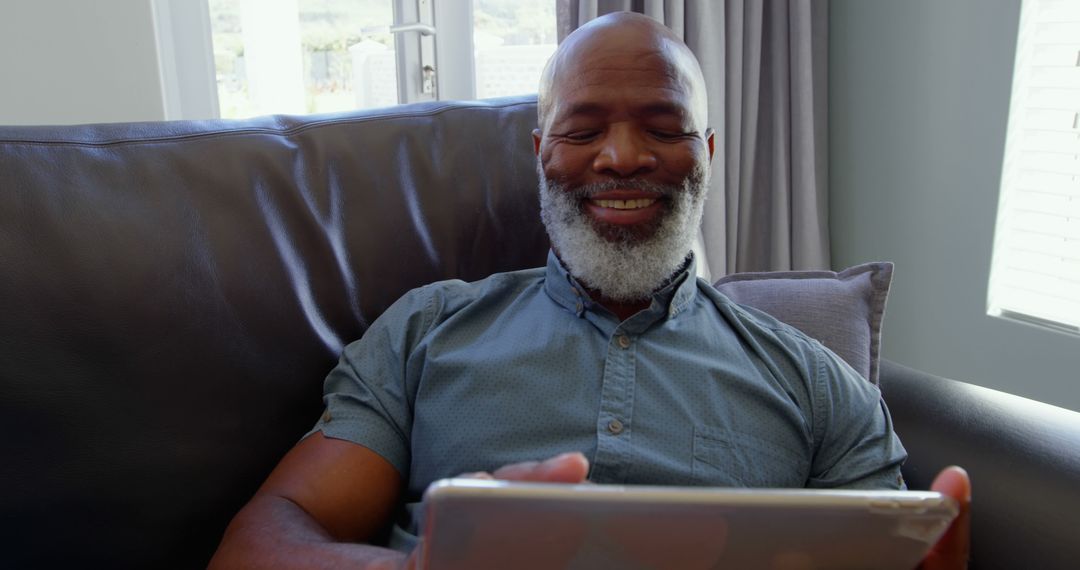 Senior Man Relaxing on Sofa Using Tablet and Smiling - Free Images, Stock Photos and Pictures on Pikwizard.com