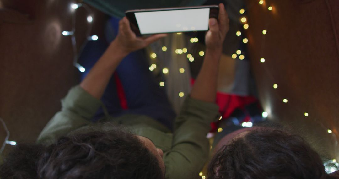 Friends Watching Tablet Inside Blanket Fort with String Lights - Free Images, Stock Photos and Pictures on Pikwizard.com