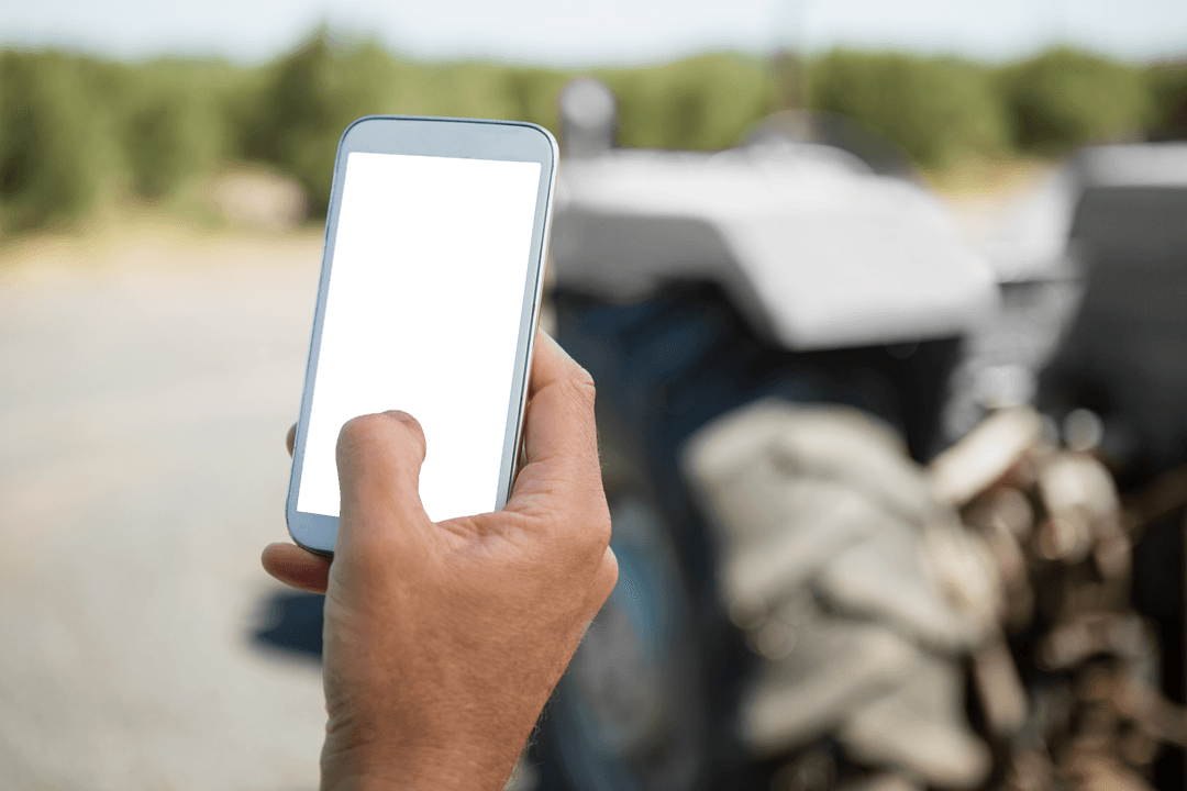 Worker Hand Holding Smartphone Near Blurry Tractor Landscape