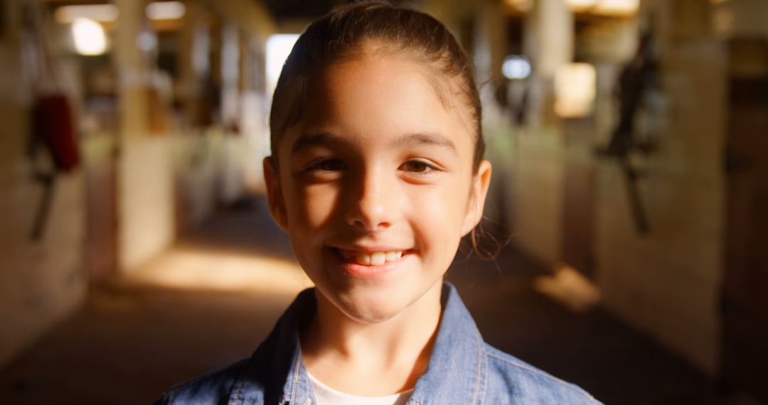 Smiling Girl Wearing Denim Jacket in Sunlit Barn - Free Images, Stock Photos and Pictures on Pikwizard.com