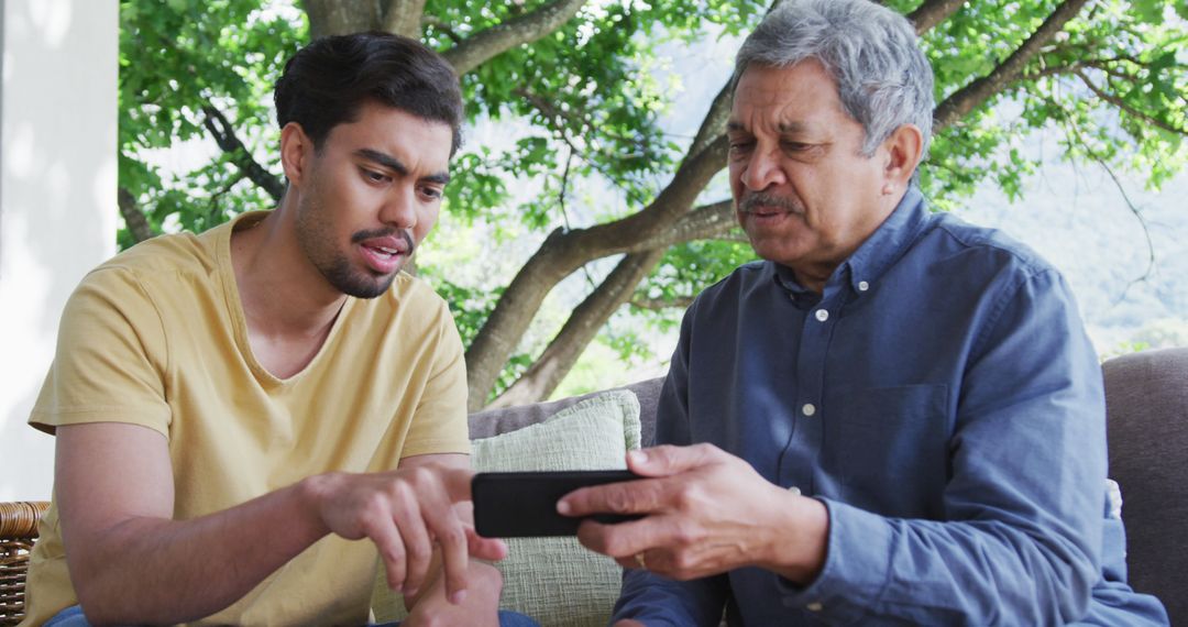 Young Man Teaching Elderly Man to Use Smartphone Outdoors - Free Images, Stock Photos and Pictures on Pikwizard.com