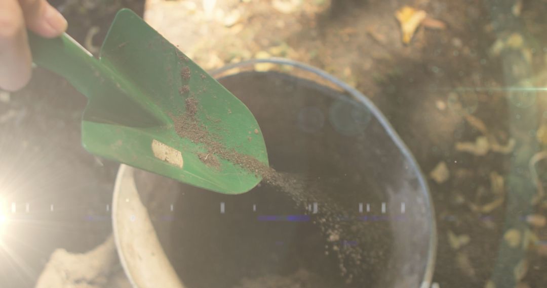 Hands Scatting Soil Intro Bucket with Garden Spade