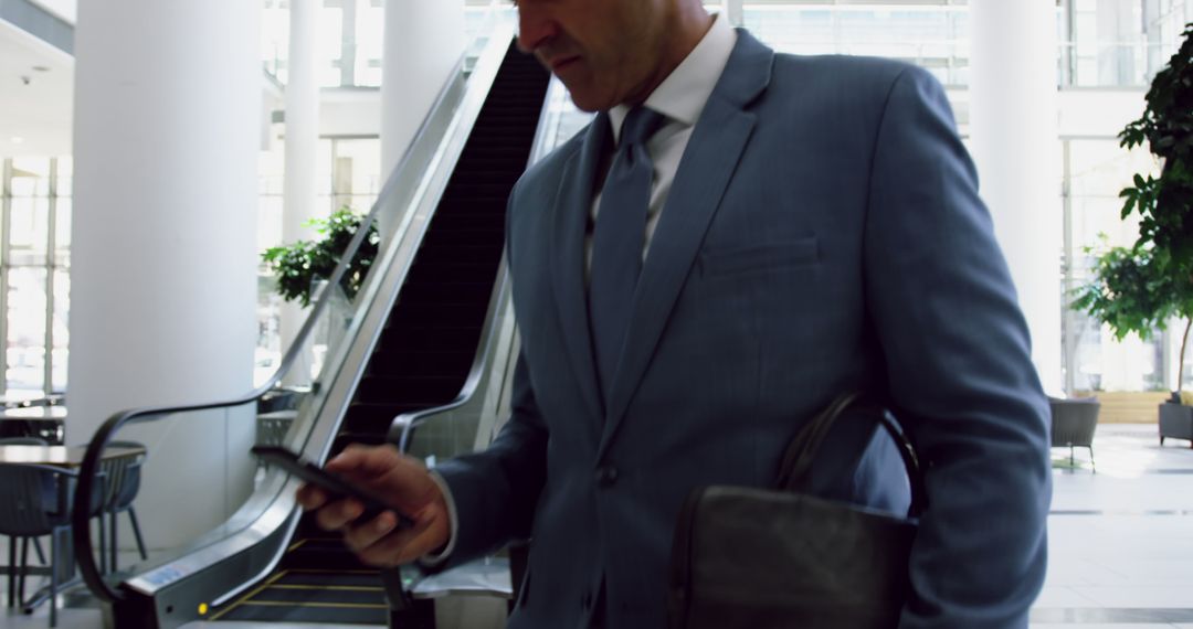 Businessman Using Smartphone in Modern Office Lobby - Free Images, Stock Photos and Pictures on Pikwizard.com