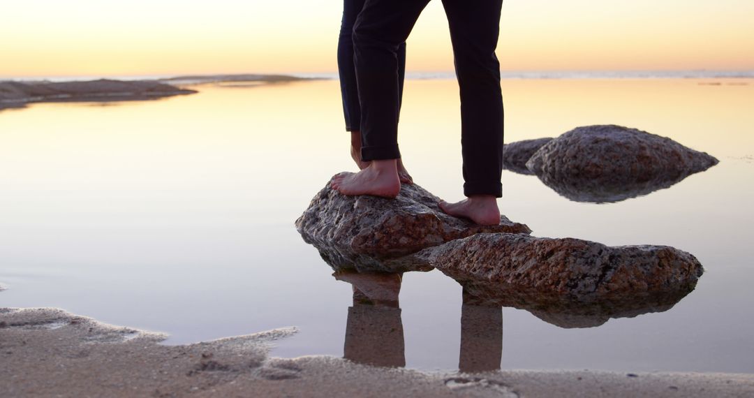 Close-Up of Person's Feet Standing on Rocks in Calm Coastal Water at Sunset - Free Images, Stock Photos and Pictures on Pikwizard.com