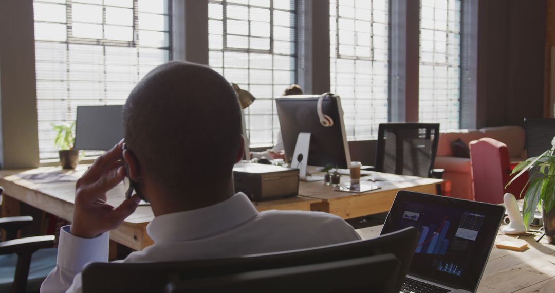 Businessman Discussing on Phone in Modern Office with Laptop