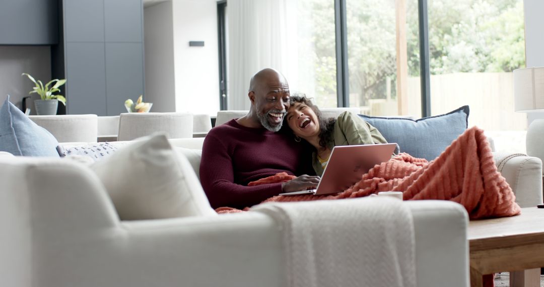 Happy Couple Using Laptop Relaxing on Couch at Home