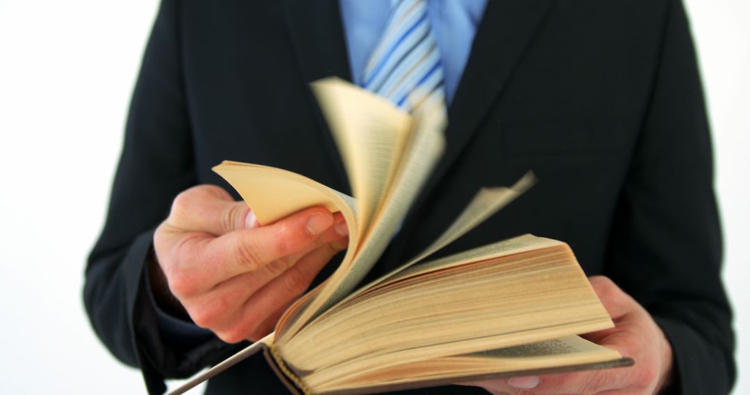 Businessman Reading Through Book with Pages Flipping - Free Images, Stock Photos and Pictures on Pikwizard.com