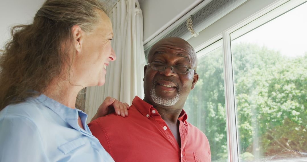 Smiling Senior Couple Embracing by Window in Bright Home