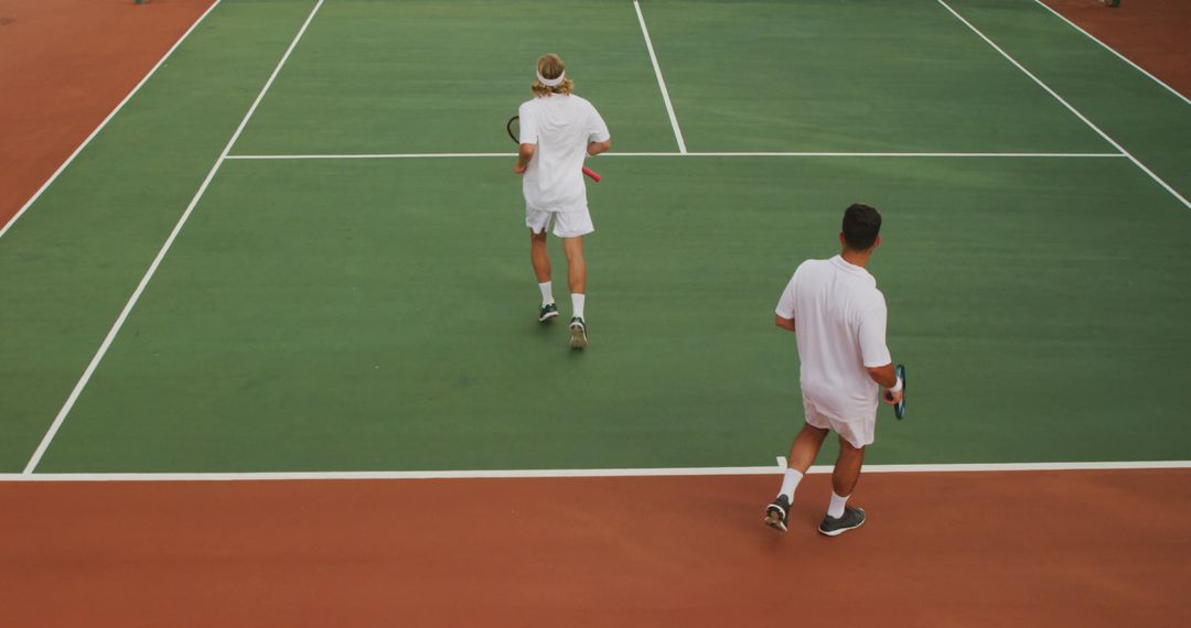 Two Men Playing Tennis on Green Court - Free Images, Stock Photos and Pictures on Pikwizard.com