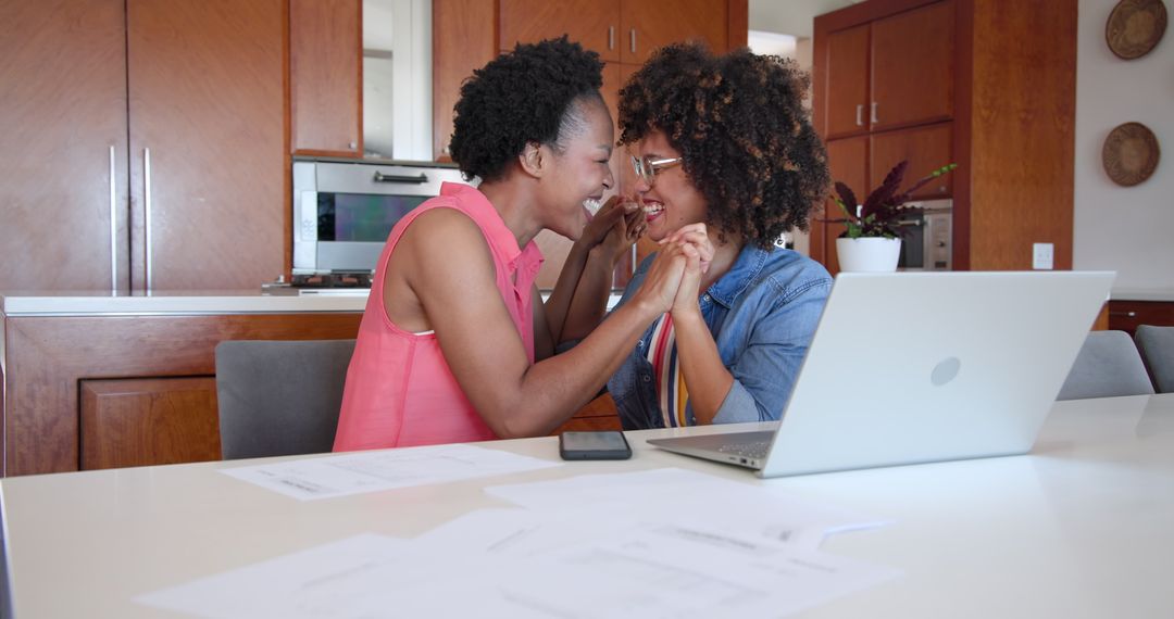 Female Couple Collaborating at Home with Documents and Laptop