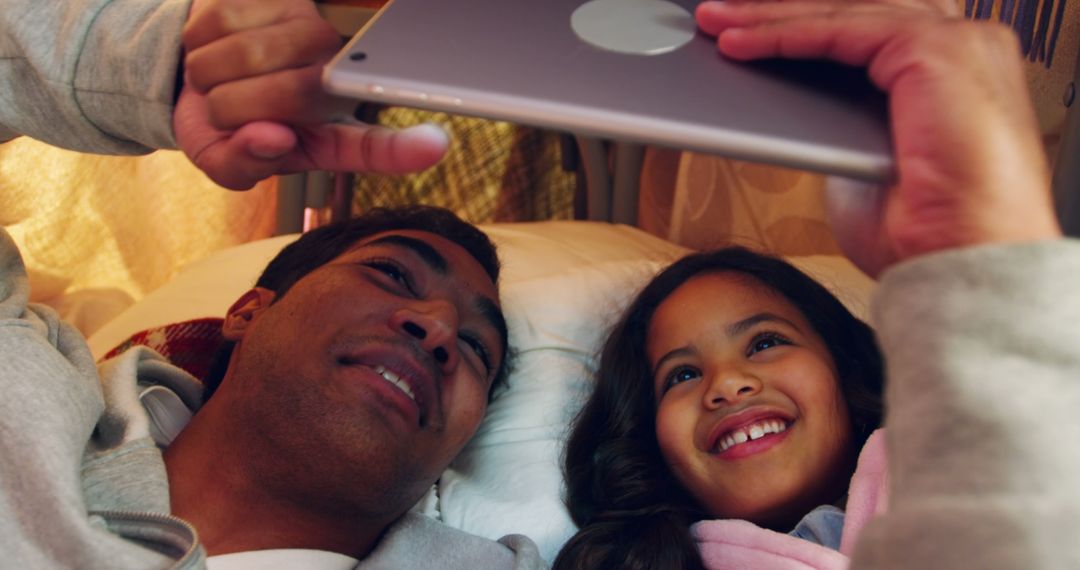 Smiling Father and Daughter Using Tablet Computer in Cozy Tent - Free Images, Stock Photos and Pictures on Pikwizard.com