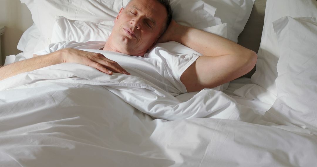 Middle-aged man peacefully sleeping in white bed - Free Images, Stock Photos and Pictures on Pikwizard.com