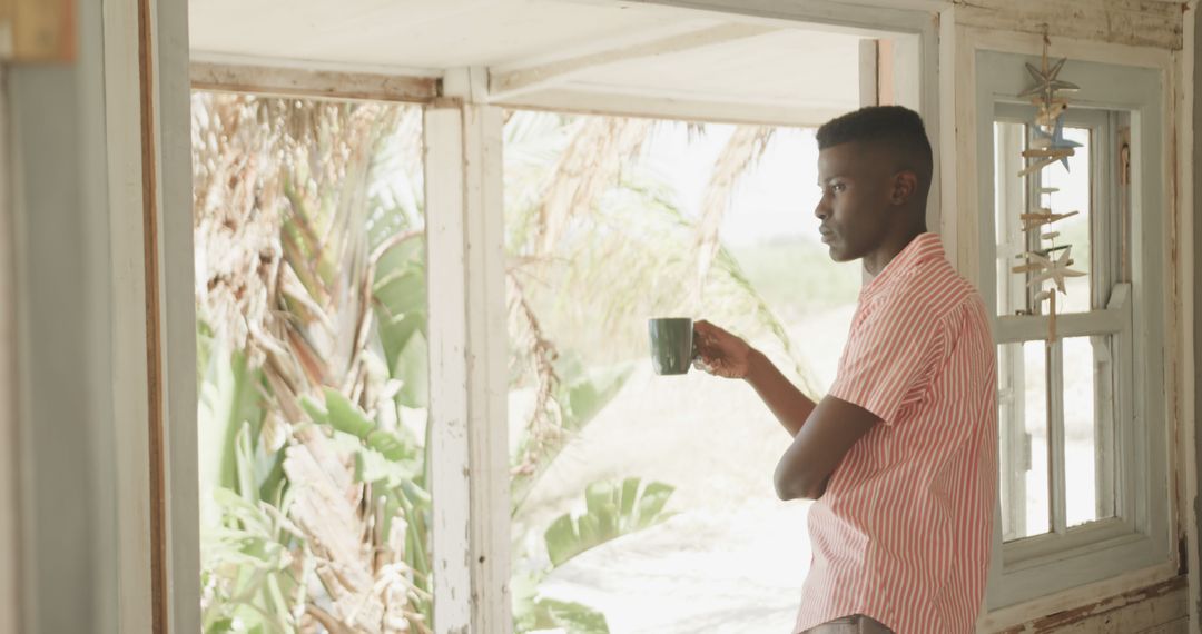 Man Drinking Coffee by the Window with Tropical Plants Outdoors - Free Images, Stock Photos and Pictures on Pikwizard.com