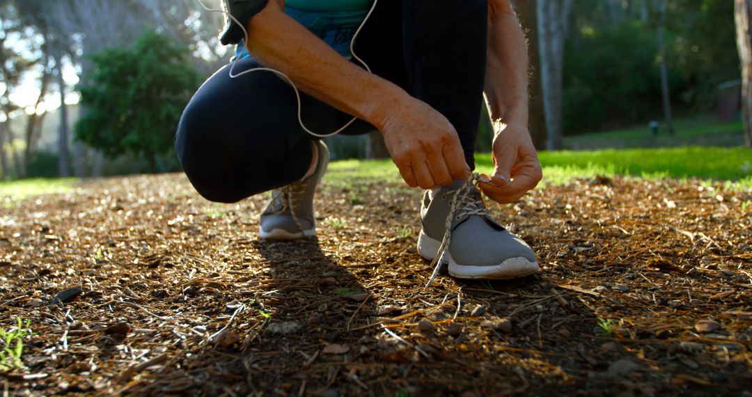 Person tying running shoes in outdoor park during workout - Free Images, Stock Photos and Pictures on Pikwizard.com