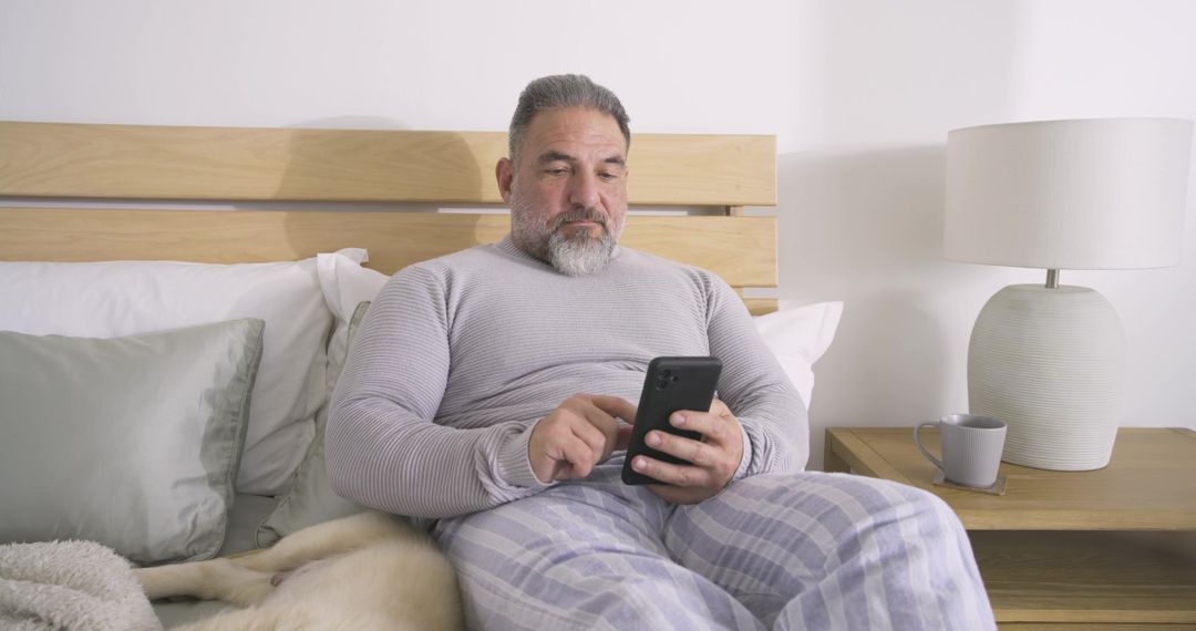 Middle Aged Man Relaxing in Bedroom Browsing on Smartphone