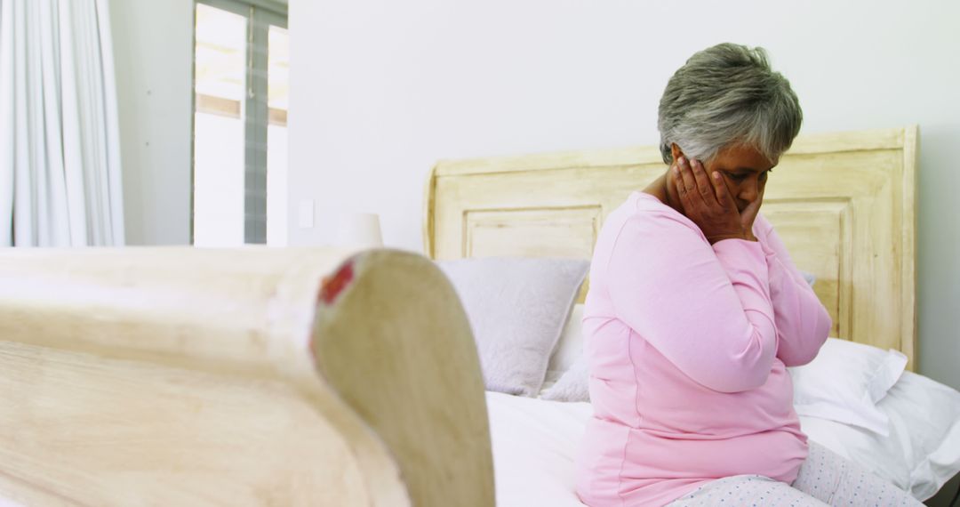 Senior Woman Looking Worried Sitting on Bed in Brightly Lit Room - Free Images, Stock Photos and Pictures on Pikwizard.com