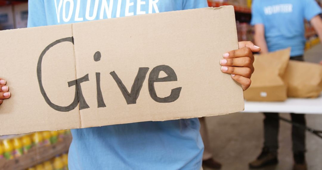 Volunteer Holding 'Give' Sign for Charity Drive - Free Images, Stock Photos and Pictures on Pikwizard.com