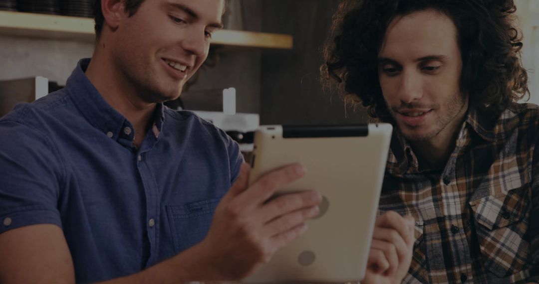 Two Men Collaborating with Tablet in Coffee Shop Environment