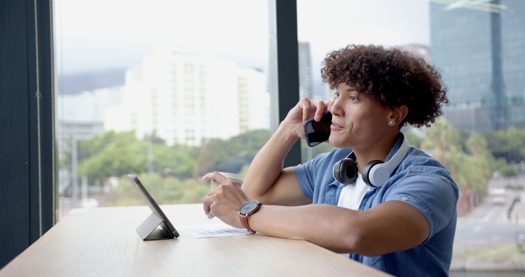 Man Engaging in Multitasking with Smartphone and Tablet in Urban Office
