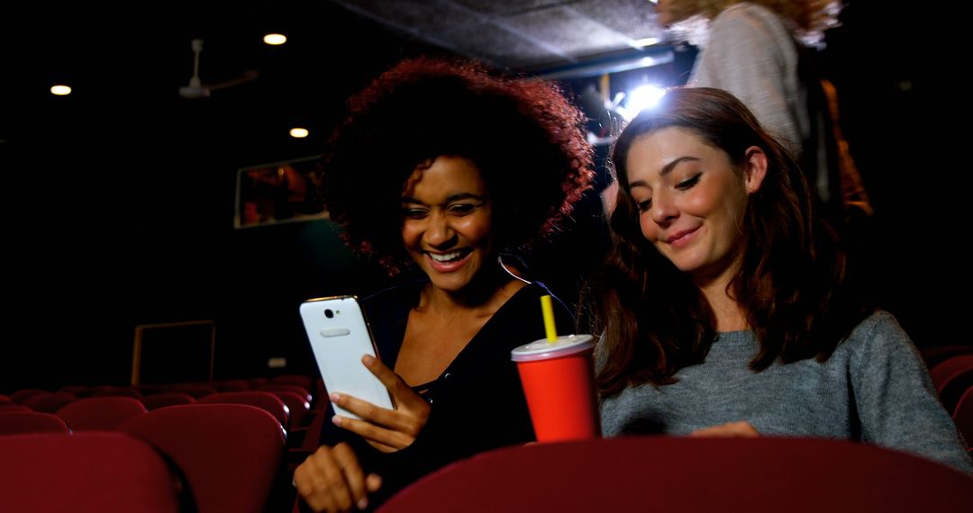 Friends Enjoying Smartphone Moment in Movie Theater - Free Images, Stock Photos and Pictures on Pikwizard.com