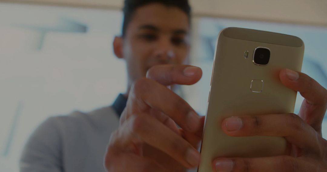 Man Using Gold Smartphone with Focus on Device