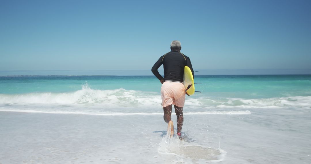 Senior Man Running into Ocean with Surfboard on Sunny Beach - Free Images, Stock Photos and Pictures on Pikwizard.com