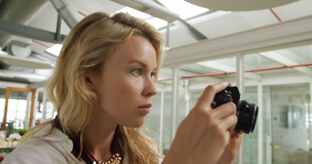 Blonde Woman Holding Camera in Modern Office - Free Images, Stock Photos and Pictures on Pikwizard.com