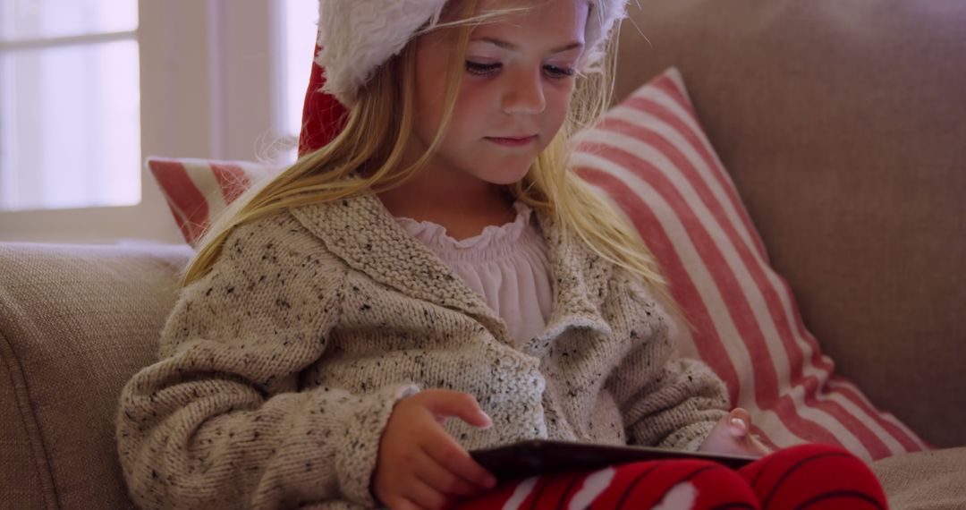 Child Wearing Santa Hat Using Digital Tablet During Christmas Holiday - Free Images, Stock Photos and Pictures on Pikwizard.com