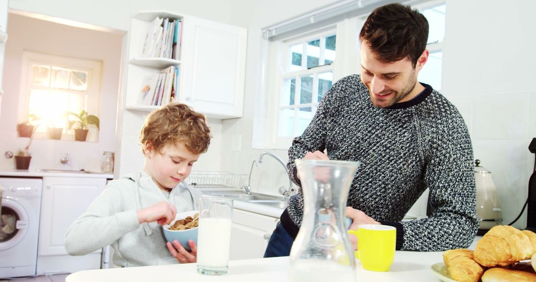 Father and Son Enjoying Breakfast Together in Bright White Kitchen - Free Images, Stock Photos and Pictures on Pikwizard.com