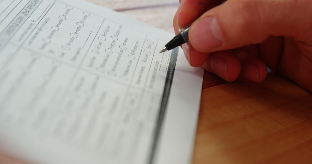 Person Filling Out a Form with Pen on Wooden Surface - Free Images, Stock Photos and Pictures on Pikwizard.com