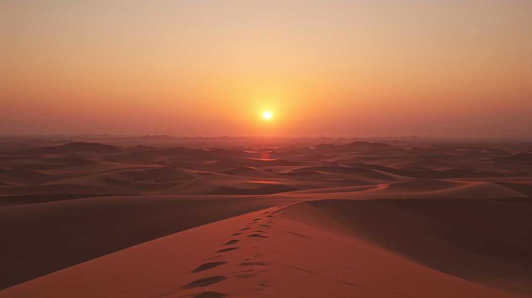 Golden Sunrise Over Rolling Sand Dunes with Footprints Leading Across Vast Desert